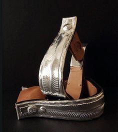 a pair of silver shoes sitting on top of a black surface