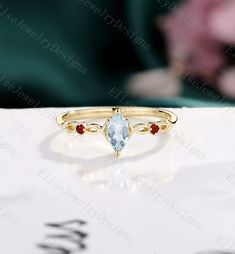 a gold ring with an aqua blue topazte and red garnets on it