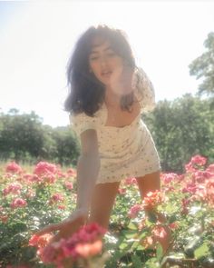 a woman kneeling down in a field full of flowers