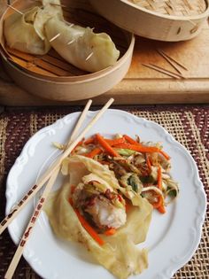 a white plate topped with meat and veggies next to chopsticks on a table