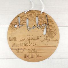 a personalized wooden ornament hanging on a white wood wall with name and date