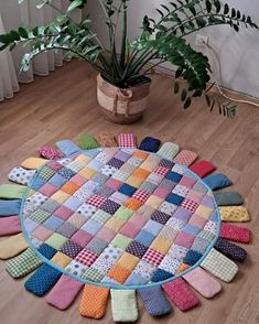 a patchwork rug on the floor next to a potted plant