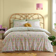 a bedroom with yellow walls and a bed covered in colorful bedspread, pillows and blankets