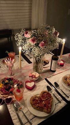 a table topped with pizzas and glasses filled with wine next to flowers on top of a table