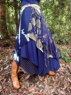 a woman is standing in the woods wearing a blue dress with gold flowers on it