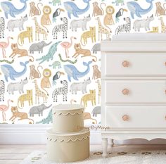 a white dresser sitting next to a wall with animals on it