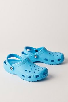 A cult classic, these effortless slip-on clogs from Crocs are featured in their instantly recognizable silhouette with a perforated upper, water-friendly design, and pivoting heel strap. **Features:** Slip-on style, lightweight, water-friendly and buoyant uppers, ventilation ports, pivoting heel strap, textured footbed, tread outsole **Why We | Crocs Classic Clogs at Free People in Blue, Size: US 7 Crocs Classic Clogs, Friendly Design, Strap Heels, Clogs, Free People, Slip On, Heels, Water, Blue