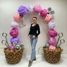 a woman standing in front of a display of yarn balls and knitting needles with mice