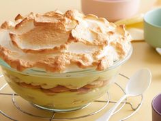 a pie sitting on top of a glass plate next to two cups and spoons