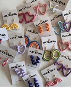 many different colored earrings are on display in front of some cards with the words matena