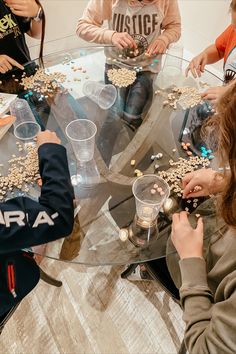 several people sitting around a glass table with beads on it