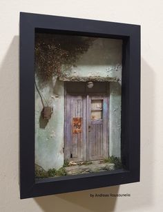 a framed photograph of an old door on a wall with a cat in the doorway