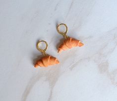 two small orange carrots hanging from gold earrings