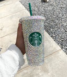 a person holding up a starbucks cup covered in swarozak and sparkles