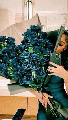 a woman taking a selfie with her cell phone and holding a bouquet of blue roses