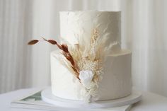 a white wedding cake decorated with feathers and flowers