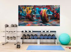 an exercise room with colorful graffiti on the wall and gym equipment in front of it