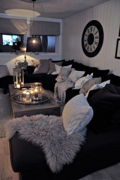 a living room filled with black couches and pillows on top of eachother