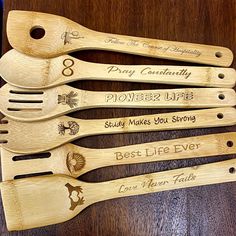 five wooden utensils with engraved names on them sitting on top of a table