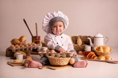 a baby wearing a chef's hat sitting in a basket with bread on it