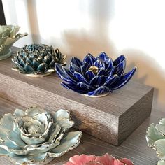 four ceramic flowers sitting on top of a wooden stand