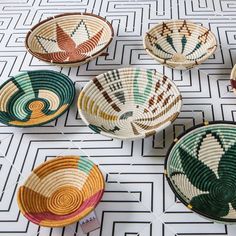 several woven baskets sitting on top of a white floor next to an orange and green plant