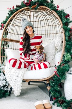 a woman sitting in a chair with her dog wearing a striped sweater and slippers