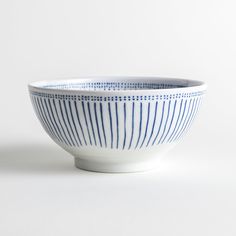 a blue and white striped bowl sitting on top of a white tablecloth covered floor