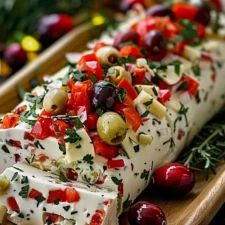 an appetizer with olives, tomatoes and cheese on a wooden platter