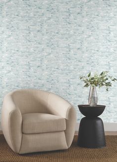 a chair and vase in front of a wallpapered room with blue waves on it