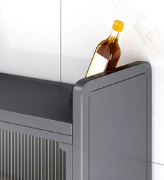 a bottle of wine sitting on top of a gray cabinet next to a white wall