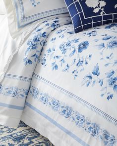 a blue and white comforter set with flowers on the pillowcase, along with matching pillows