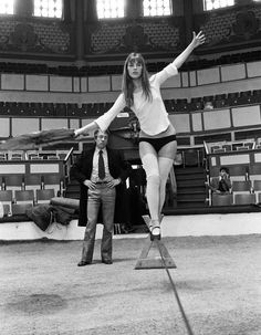 a woman standing on top of a pair of skis in front of a man