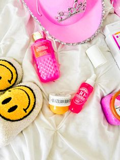 the contents of a woman's purse laid out on a white bed with pink accessories