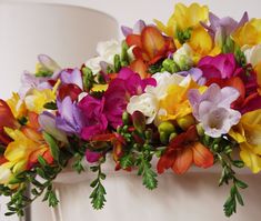 a bunch of colorful flowers sitting on top of a white chair