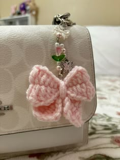 a white purse with a pink crocheted bow on it's front pocket