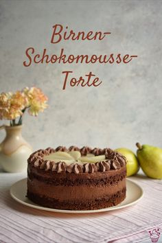 a chocolate cake sitting on top of a white plate next to two green pears