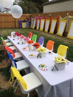 a long table is set up with colorful chairs and decorations for an outdoor birthday party