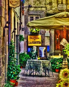 an alleyway with tables and umbrellas on the side walk in front of a building