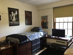 a bedroom with posters on the wall and a small bed in front of a flat screen tv