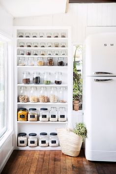 a white refrigerator freezer sitting inside of a kitchen next to a shelf filled with food