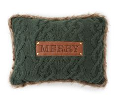 a green cable knit pillow with the word merry on it and a brown leather patch