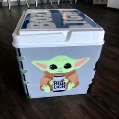 a cooler with an image of the baby yoda on it's side, sitting on a wooden floor