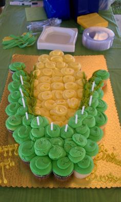 cupcakes with green frosting and yellow icing are arranged on a table