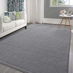 a living room with a white couch and gray rugs on the floor in front of a window