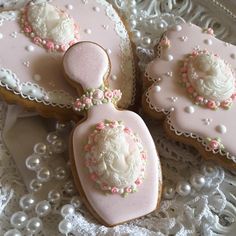 three decorated cookies sitting on top of a white lace doily with pink and white frosting