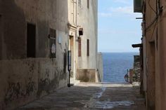 an alley way leading to the ocean on a sunny day with no one in sight