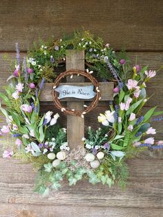 a cross decorated with flowers, greenery and a sign that says we are born