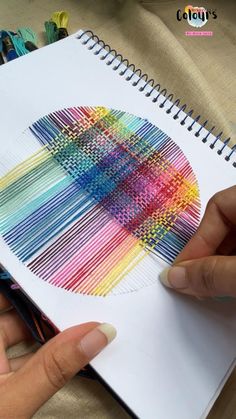 a person is drawing on paper with colored pencils