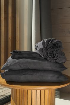 several folded blankets sitting on top of a wooden table